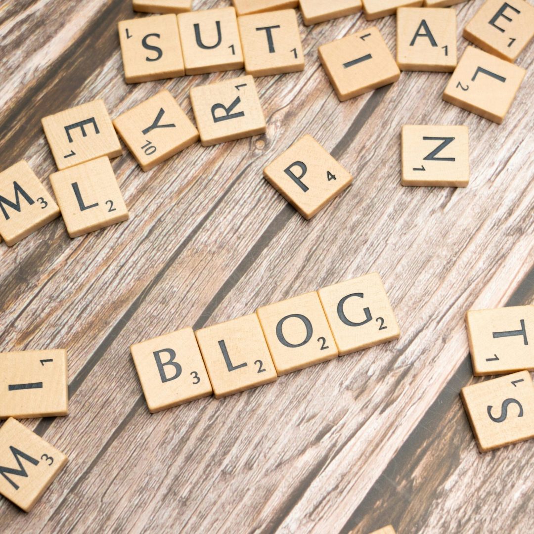 Scattered wooden letter tiles spelling 'Blog' on a rustic wood background.
